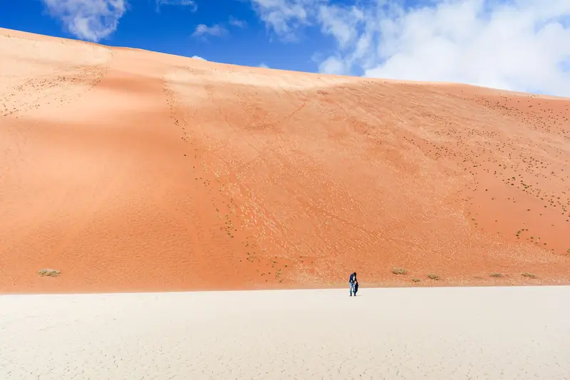 Ein Wanderer am Fuß einer riesigen roten Düne in der Namib