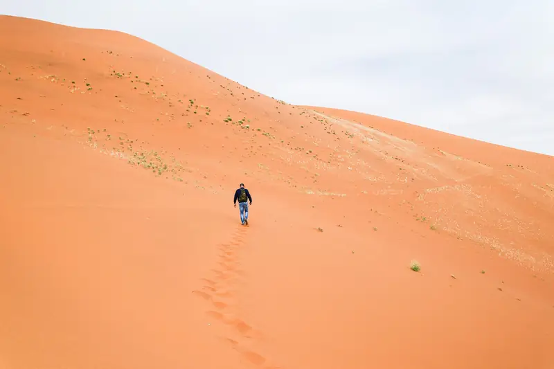 Ein Reisender läuft eine rote Düne in Namibia hinauf
